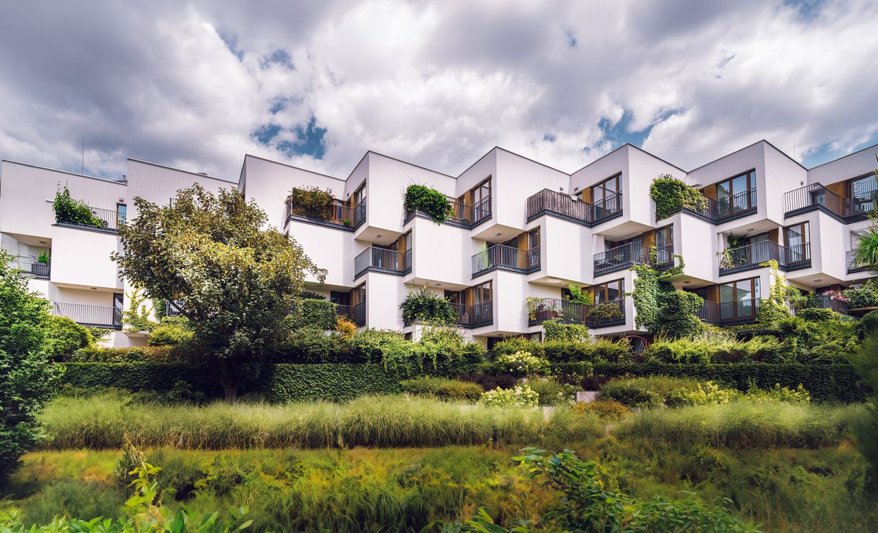 Contemporary apartment complex featuring sustainable architecture with lush greenery and open balconies.